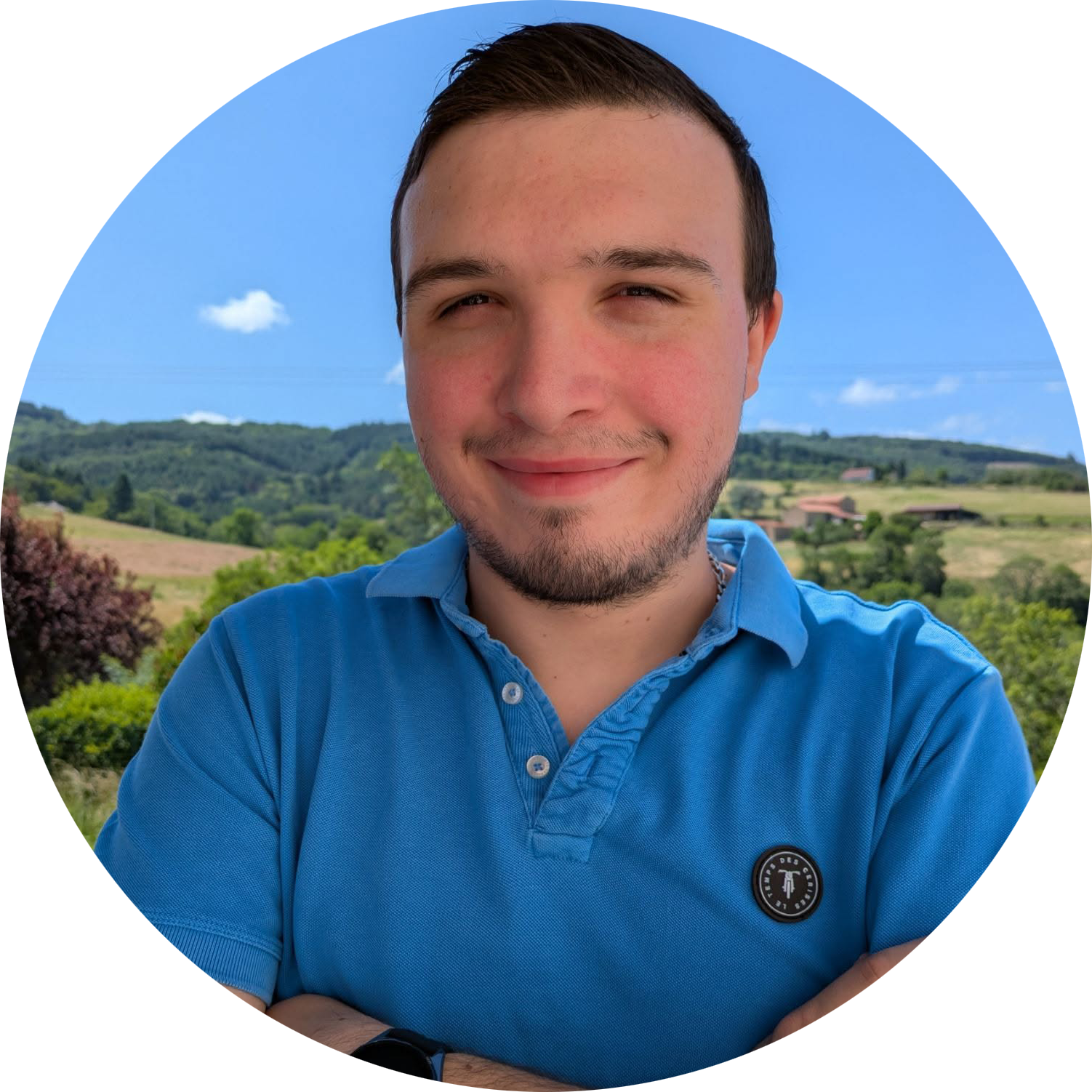 Photo de Killian Barraud, le fondateur du site, portant un polo bleu. Il sourit et est à l'extérieur, avec pour toile de fond un paysage de collines verdoyantes et un ciel bleu limpide.